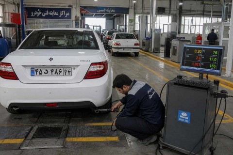 تکنسین در حال انجام تست آلایندگی اگزوز خودرو در مرکز معاینه فنی