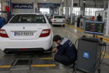 تکنسین در حال انجام تست آلایندگی اگزوز خودرو در مرکز معاینه فنی